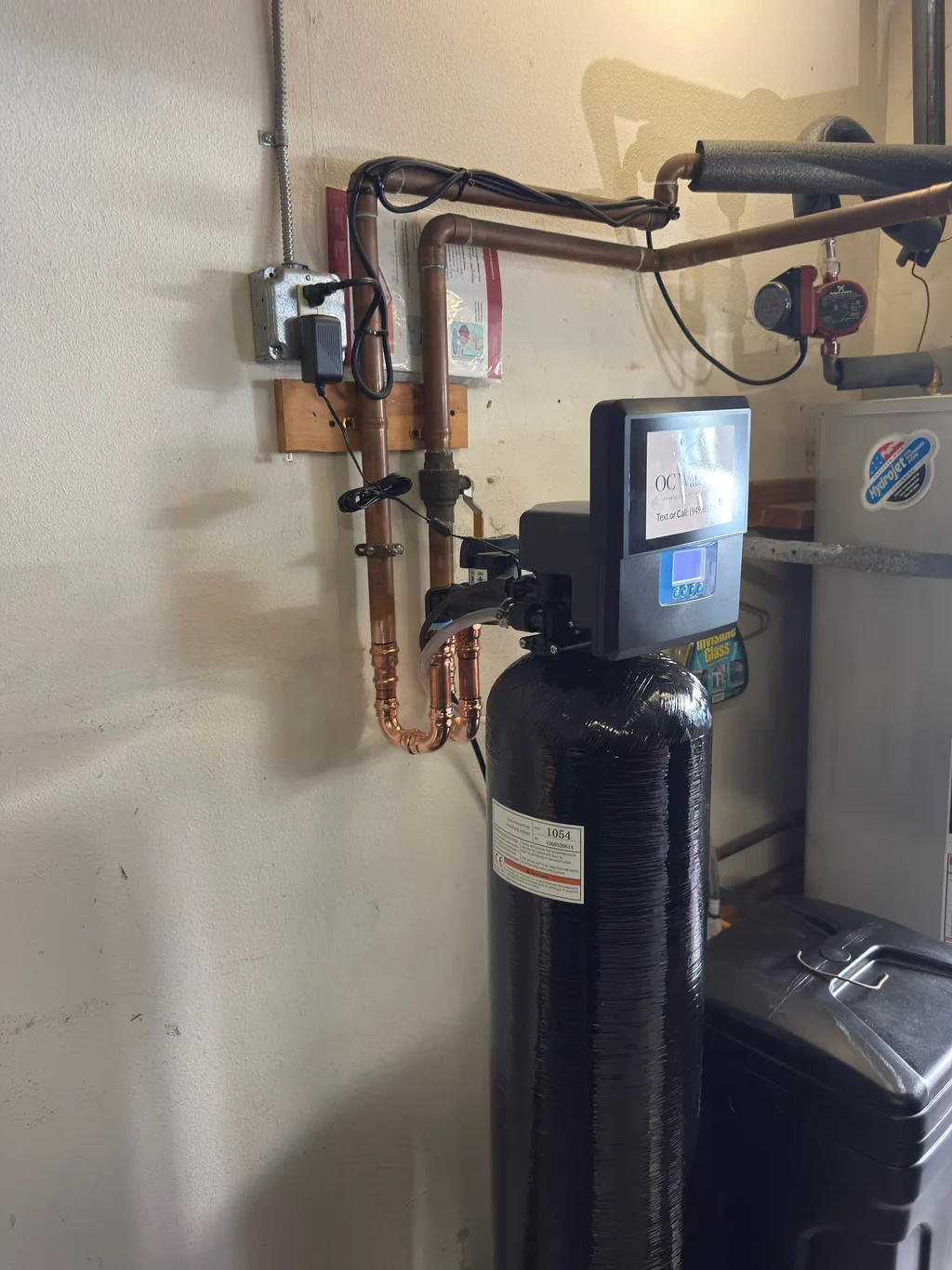 A garage installation with bright copper supply loops running into a black tank and digital valve head